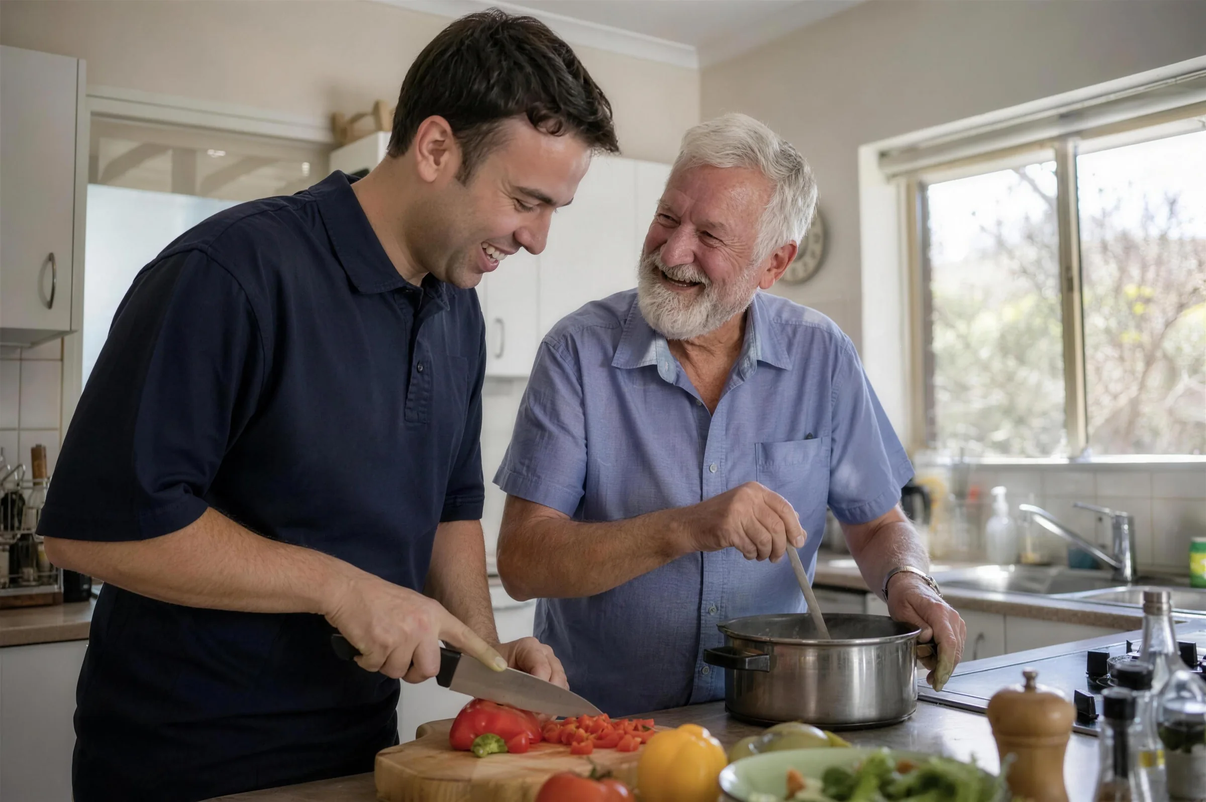 A carer and an older man cooking together at a kitchen bench, chopping vegetables